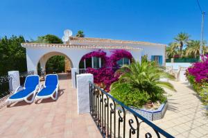 patio z niebieskimi krzesłami i fioletowymi kwiatami w obiekcie CALALGA сasa frente a la playa con piscina privada w mieście Calpe