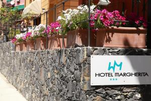 a sign for a hotel margherita with flowers on a stone wall at Hotel Margherita in Monterosso al Mare