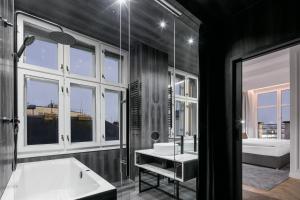 a bathroom with a tub and a sink and windows at Pytloun Boutique Hotel Prague in Prague