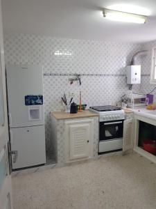 a kitchen with a stove and a refrigerator at Maison les Palmiers 300m de la plage in Aghīr