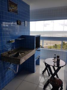 - une cuisine carrelée de bleu avec un évier et une table dans l'établissement Apartamento pé na areia, à Praia Grande