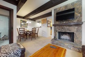 a living room with a stone fireplace with a television at Lionshead Apartments in Vail