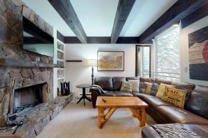 uma sala de estar com um sofá de couro e uma lareira de pedra em Lionshead Apartments em Vail