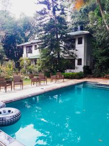 a swimming pool with chairs and a house in the background at St Bridget's Country Bungalow in Kandy