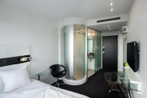 
a bathroom with a shower and a bed at Wakeup Copenhagen - Carsten Niebuhrs Gade in Copenhagen
