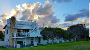 a white building with trees and a cloudy sky at Gouritz Guesthouse in Gouritzmond