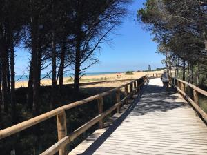 a woman walking down a wooden boardwalk near the beach at Ville Nautilus in Bibione