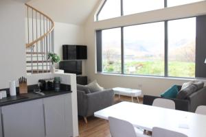a living room with a table and chairs and windows at Wilderness Apartments in Fort William