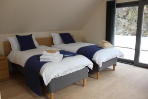 a bedroom with three beds with blue and white sheets at Wilderness Apartments in Fort William