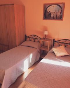 a bedroom with two beds and a table with a lamp at La casa di nonna Rosa in Isola delle Femmine