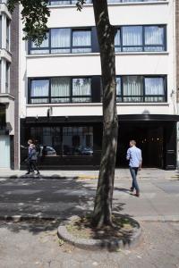 a man and woman walking down a street next to a tree at Hotel Carlton in Ghent