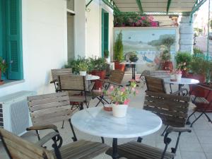 eine Außenterrasse mit Tischen, Stühlen und Blumen in der Unterkunft Orfeas Hotel in Mytilini