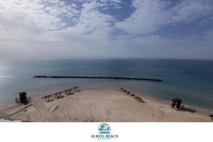 - une vue sur une plage avec un groupe de parasols dans l'établissement Almog Haifa Israel Apartments מגדלי חוף הכרמל, à Haïfa