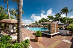 a patio area with a pool, chairs, and umbrellas at Livingstone Jan Thiel Resort in Willemstad
