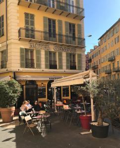 pessoas sentadas em mesas fora de um hotel em Hôtel Le G (ex Le Genève) em Nice