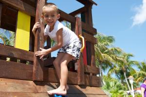 a young boy is sitting on a wooden bench at Livingstone Jan Thiel Resort in Willemstad