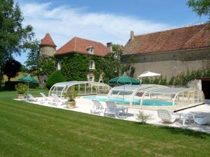 a pool with chairs and umbrellas in front of a house at Château de Ribourdin in Chevannes