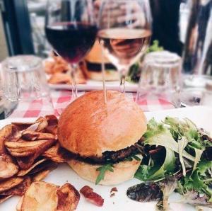 a sandwich and french fries on a table with glasses of wine at Hôtel Le G (ex Le Genève) in Nice