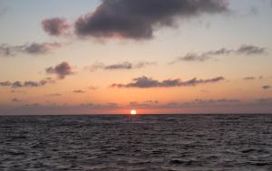 una puesta de sol sobre el océano con el sol en el horizonte en 139 Ferienhaus am Wattenmeer, en Sande