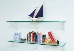 a glass shelf with a toy boat and books at Rusty Pelican Pristine Apt. in La Gaulette