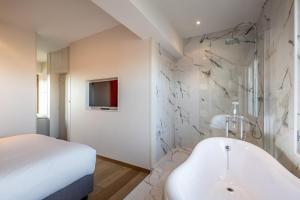 a white bathroom with a tub and a bed at Hotel Carlton in Ghent