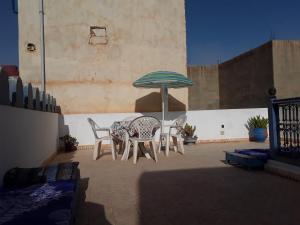 a patio with a table and chairs and an umbrella at La Maison Bleue in Sidi Ifni
