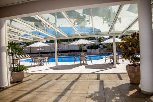 a pool with tables and umbrellas in a building at Itu Plaza Hotel in Itu