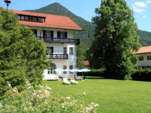 ein Haus mit einem Garten mit Stühlen und Bäumen in der Unterkunft Hotel zur Post in Kreuth