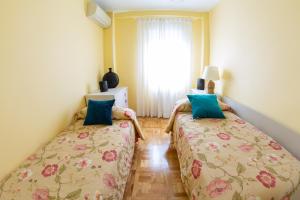 2 Betten in einem kleinen Zimmer mit Fenster in der Unterkunft Apartamentos Duque Martinez Izquierdo. in Madrid