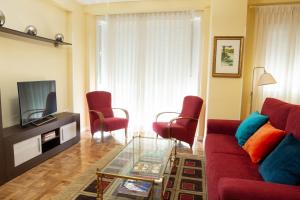 sala de estar con sofá rojo y sillas en Apartamentos Duque Martinez Izquierdo. en Madrid