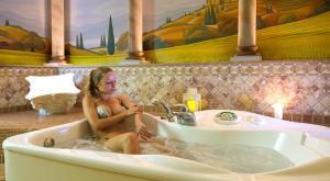 a woman is sitting in a bath tub at Residence Eden in Peschiera del Garda +48 photos