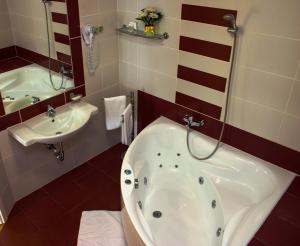 a bathroom with a tub and a sink at Calimbra Wellness Hotel Superior in Miskolctapolca