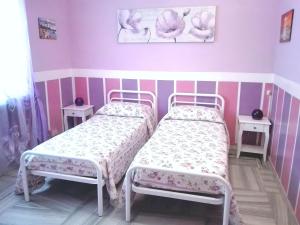 2 camas en una habitación con paredes rosas en Hotel Serenella, en Turín