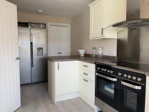 a kitchen with a black stove and a refrigerator at Newly Renovated & Spacious House in Seahouses