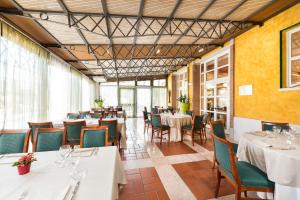 a restaurant with white tables and chairs and windows at Hotel Villa Malaspina in Castel d'Azzano