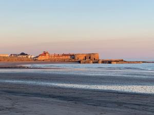 a view of the beach with a castle in the distance at Newly Renovated & Spacious House in Seahouses