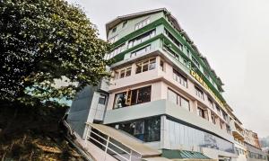 a tall white building with green accents at Dekeling Hotel in Darjeeling