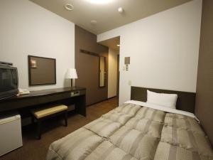 um quarto com uma cama, uma secretária e uma televisão em Hotel Route-Inn Court Ina em Ina