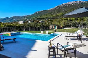 una piscina con 2 sillas y una sombrilla en Home Away from home with outdoor pool, botanical garden and a beautiful sea view, en Kaštela