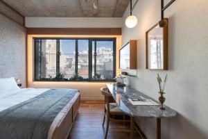 Schlafzimmer mit einem Bett, einem Schreibtisch und einem Fenster in der Unterkunft Ergon House Athens in Athen