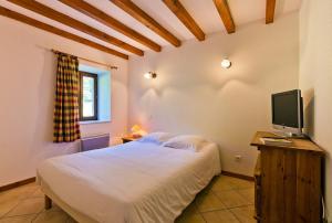 a bedroom with a white bed and a television at AUBERGE DE LA MORENO in Saint-Genès-Champanelle