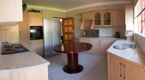 a kitchen with a wooden table and a refrigerator at Bara Guesthouse in Welkom