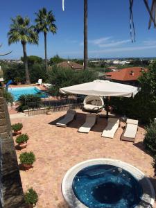 a patio with an umbrella and a swimming pool at Le Palme Residenza Estiva in Martinsicuro