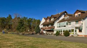 un gran edificio blanco con césped delante en Gasthaus Zur Hardtmühle, en Alsfeld