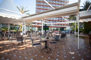 um pátio com cadeiras e mesas e um edifício em Hotel Obelisco em Playa de Palma