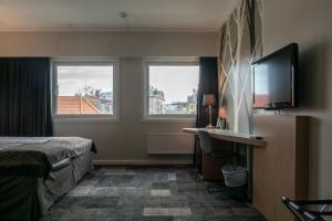 a hotel room with a bed and a flat screen tv at City Living Sentrum Hotel in Trondheim