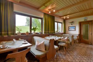 un restaurant avec des tables et des chaises en bois ainsi que des fenêtres dans l'établissement Obinghof, à Söll