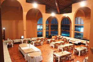 a restaurant with white tables and chairs and windows at Rio Poty Hotel Praia in Luis Correia