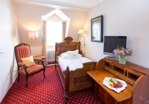 イッセルブルクにあるロマンティック パークホテル ヴァッサーブルク アンホルトのベッドとテレビが備わるホテルルームです。