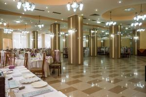 un salón de banquetes con mesas y sillas blancas y lámparas de araña en Hotel Traian, en Brăila